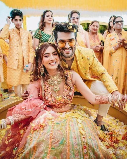 haldi photo of a bride with a male friend and family together in the background